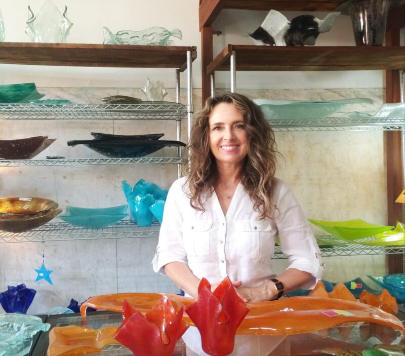 Daniela Malfatti em sua mesa com peças de vidro feitas artesanalmente